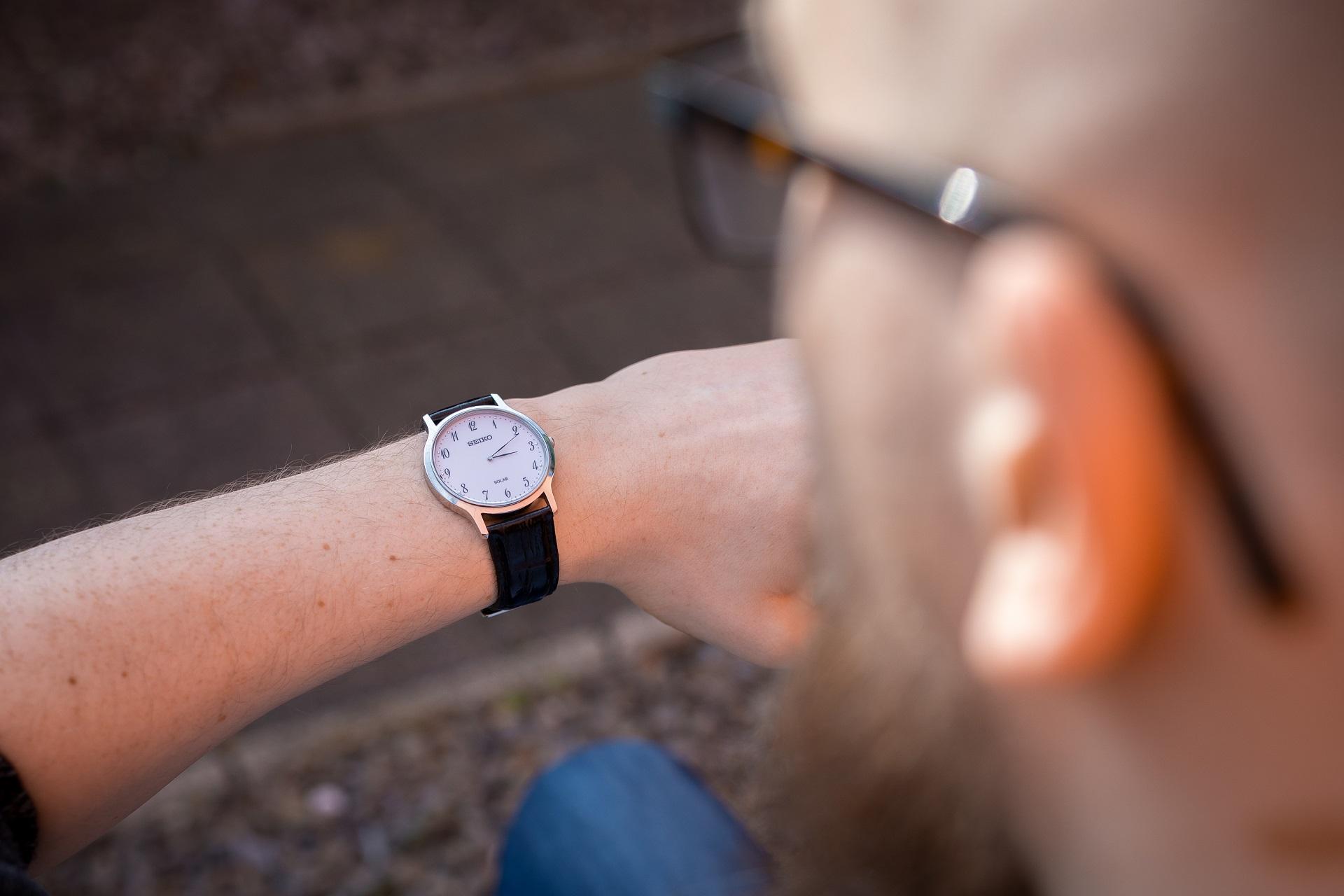Mann schaut auf seine Armbanduhr