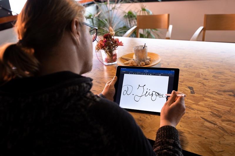 junger Mann unterschreibt auf einem Tablet