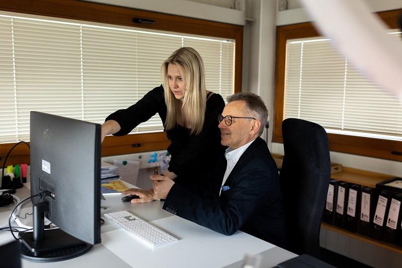 junge Frau zeigt sitzendem Businessmann auf dem Bildschirm etwas